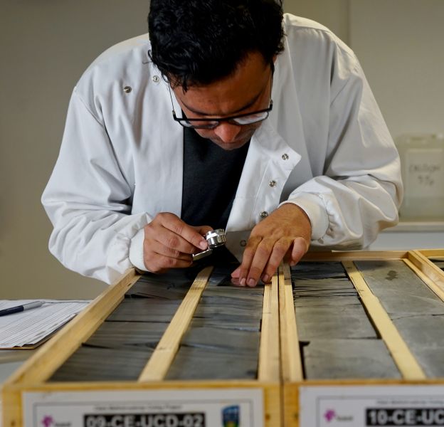 A scientist logging core in the lab using a microscope